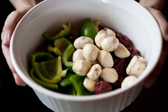 Person holding bowl of fresh cooking ingredients