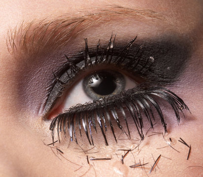 Female eye with pieces of eyelash and tears