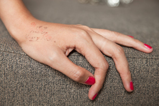 Young woman with phone number written on hand