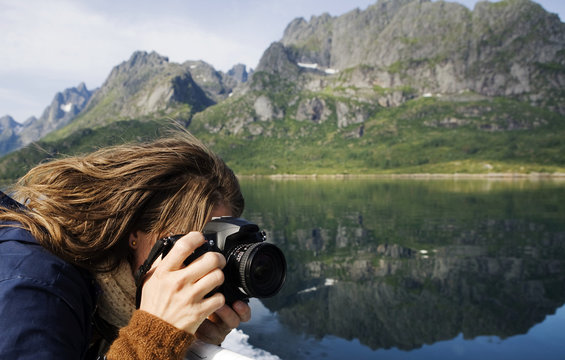 Woman taking a photograph in mountain landscape