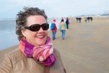 Happy mature woman posing on the beach smiling having good time.