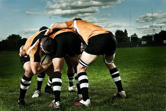 Rugby players in scrum on pitch