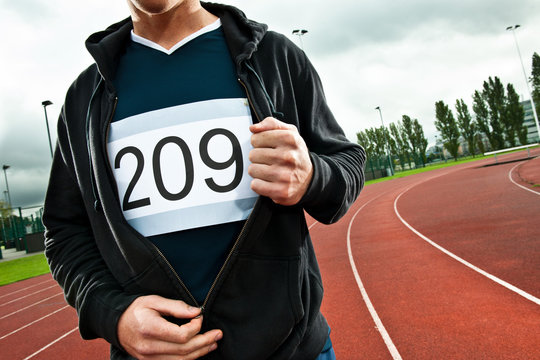 Sprinter unzipping jacket on sportstrack