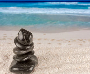 empilement de cailloux noirs sur plage des Seychelles, symbole vacances zen