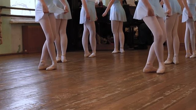 Legs of balerinas who do exercises during ballet lesson in ballet classroom