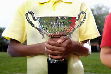 Boy holding trophy cup on school playing field