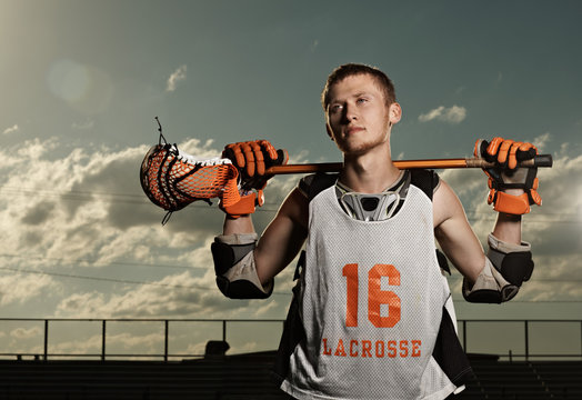 Young sportsman holding lacrosse stick in stadium