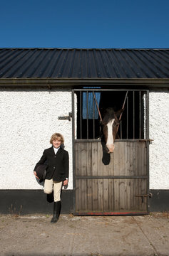 Boy standing by horse stables
