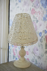 white openwork metal table lamp stands on a bedside table. Bright interior. Shabby chic