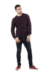 Serious confident macho casual man wearing maroon sweater looking away. Full body length portrait isolated over white studio background.