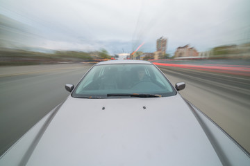 Front view of black car driving on high speed on a city at day time.