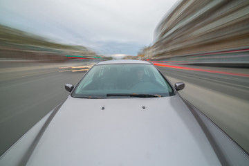 Obraz premium Front view of black car driving on high speed on a city at day time.