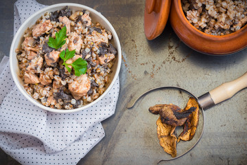 Buckwheat porridge with mushrooms and chicken in a ceramic pot on grey background. Healthy dinner. Top view. Selective focus.