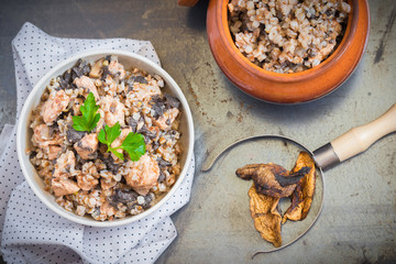Buckwheat porridge with mushrooms and chicken in a ceramic pot on grey background. Healthy dinner. 