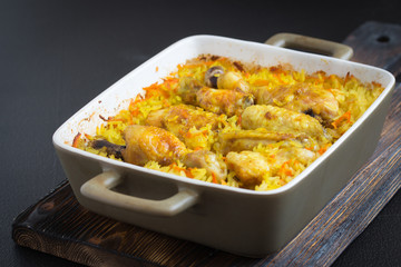 Chicken curry and rice in a ceramic baking dish on a dark background