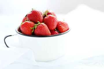 Strawberries in cup on blue wooden table