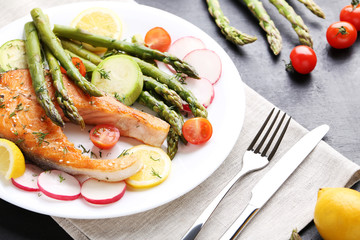 Steak of salmon with asparagus, vegetables, fork and knife