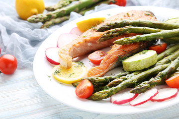 Steak of salmon with asparagus and vegetables on white plate