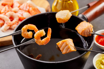 Dipping fresh salmon and prawns into a hot fondue