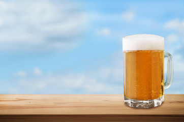 Cold beer on wooden table on sky background