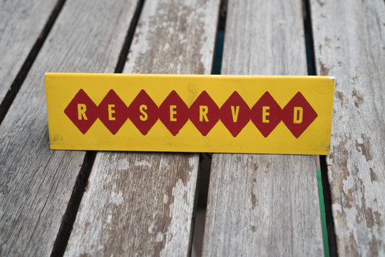 Closeup of restaurant reserved table sign over wooden table background