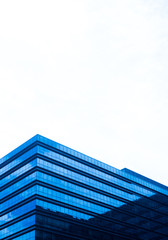 Fototapeta na wymiar Top of mirrored building against cloudy sky background