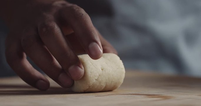 black chef hand makes a roll of dough