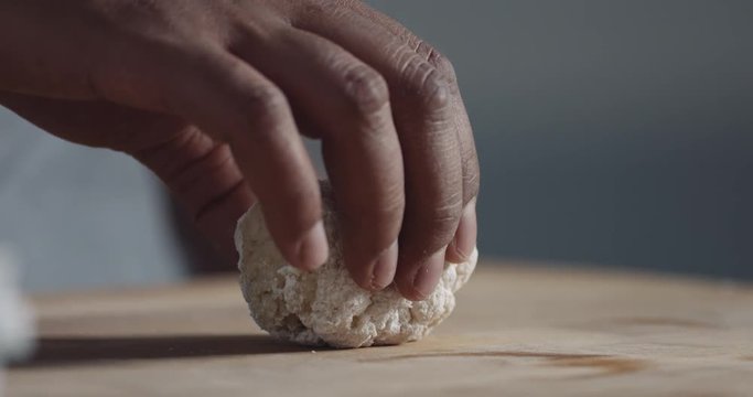 slow motion of how black man makes a roll of dough from a ball