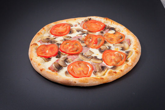Pizza with ground meat and red tomatoes on a black chalkboard