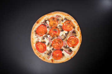 Pizza with ground meat and red tomatoes on a black chalkboard