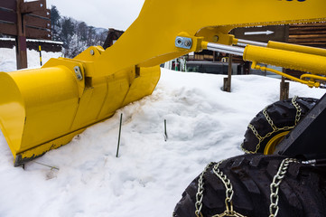 Yellow snowplow truck cleared the snow-covered road in winter day.