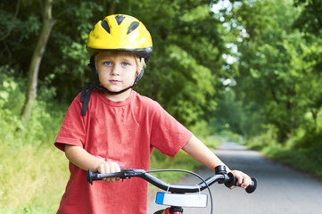 Obraz premium Young boy riding bicycle on a summer day at asphalt road. Bicycle path