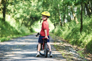 Young boy riding bicycle on a summer day at asphalt road. Bicycle path