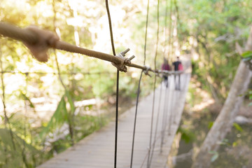 Asian hipster couple jungle trekking,  walking outdoors on the bridge in the deep fresh forest.