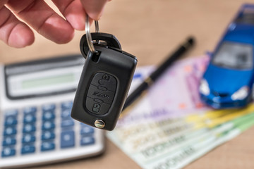 car key, toy car, euro bills on desk.