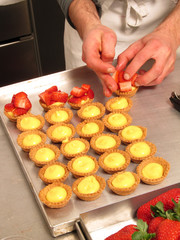 Pastelero agregando fresas a los dulces de crema .
