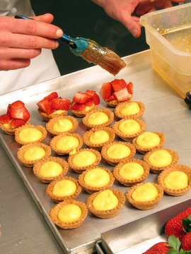 Pastelero colocando freses y caramelo a los dulces.