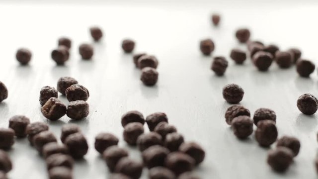Footage From brown round cocoa cacao flakes falling on white wooden table with soft focus