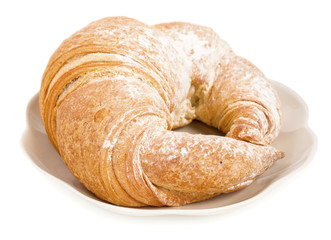 Fresh croissant on a saucer isolated on a white background, close up.