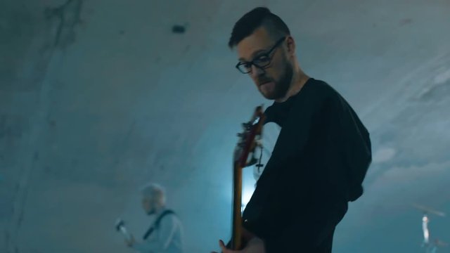 Two rock and roll guitarist and drumer playing in slowmotion underground