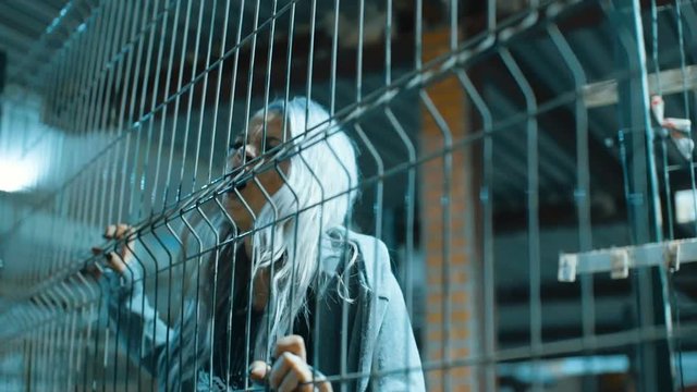 Angry rock and roll girl with grey hair inside a metal cage in slowmotion,