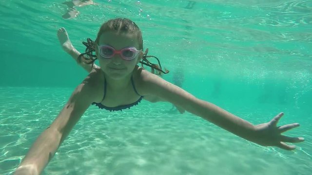 girl dives under the water in the pool