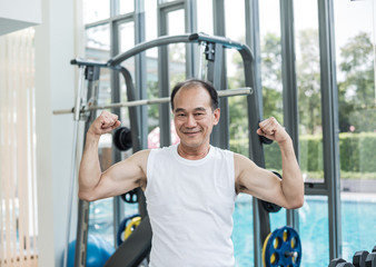 Fototapeta na wymiar Asian Senior Man Posting To Show His Muscle in The Gym After Workout - Sport and Healthcare Concept