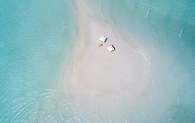 Sandbank in den Malediven mit Sonnenschirmen und Frau die sich sonnt