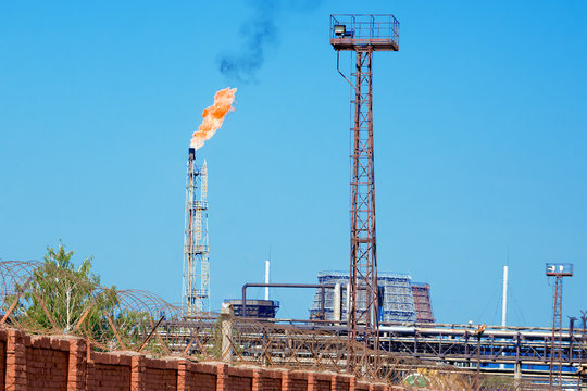 Industrial landscape with a burning torch on the pipe 