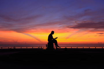 Fototapeta na wymiar Silhouette sunrise with man read book statue
