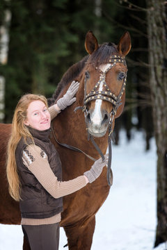 Pretty young lady with a horse in a winter forest.