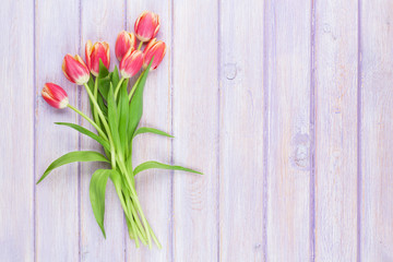 Red tulips over purple wooden table