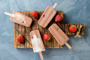 Homemade frozen ice cream chocolate popsicles with strawberry