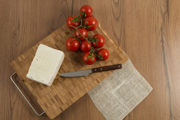tomatoes and cheese on wooden cutting board top view